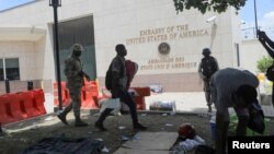 A man carries his belongings after officers of the Haitian National Police fired tear gas to clear a camp of people escaping the threat of armed gangs, in front of the US Embassy, in Port-au-Prince, Haiti, July 25, 2023.