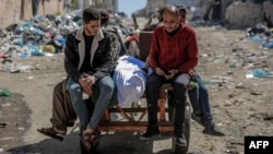 Men transport a Palestinian said to have been killed in an early morning incident when people rushed toward trucks carrying humanitarian aid in Gaza City, Feb. 29, 2024. 