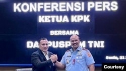 Danpuspom TNI Marsda Agung Handoko dan Ketua KPK Firli Bahuri berjabat tangan setelah konferensi pers soal penetapan dua anggota TNI sebagai tersangka korupsi di Basarnas,Senin (31/7). Keduanya menepis adanya perpecahan diantara kedua badan pimpinan mereka. (Courtesy : Mabes TNI)