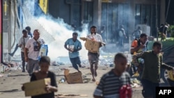 People run with merchandise as crowds leave shops with looted goods amid a state of unrest in Port Moresby, Papua New Guinea, Jan. 10, 2024. The country is discussing security assistance with China, its foreign minister says.