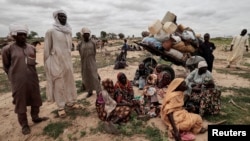 Sudanese women, who fled the conflict in Murnei in Sudan's Darfur region, wait beside their belongings to be registered by UNHCR upon crossing the border between Sudan and Chad in Adre, Chad, July 26 , 2023.
