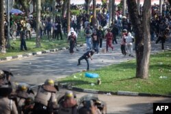 Para pengunjuk rasa melemparkan batu ke arah polisi saat demonstrasi menentang rencana pemerintah untuk mengembangkan Pulau Rempang menjadi zona ekonomi yang didanai China yang akan membuat sekitar 7.500 orang mengungsi, di kantor Badan Usaha Batam. (Foto: AFP)