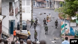 Des gens retirent un débris de la route alors que des soldats comoriens patrouillent à la suite d'une manifestation de l'opposition à Moroni le 17 janvier 2024, suite à l'annonce des résultats de l'élection présidentielle.