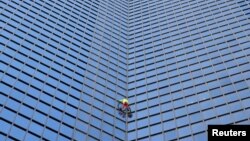 "Spiderman" Prancis Alain Robert memanjat gedung pencakar langit "Tour TotalEnergies Coupole" untuk menyerukan "Perdamaian di Timur Tengah" di Puteaux di distrik keuangan La Defense di Puteaux, dekat Paris, Prancis hari Senin (6/11). (Reuters) 