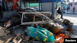 Debris and what appears to be a covered body are seen at a market in Russia-occupied Donetsk, Ukraine, Jan. 21, 2024, after what local Russian authorities said was a Ukrainian military strike.