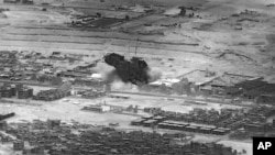 This image from video provided by the Department of Defense shows a Nov. 8, 2023, airstrike on a weapons warehouse, center, in eastern Syria. The strike targeted a facility linked to Iranian-backed militias.