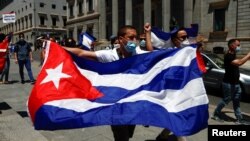 FILE - A man holds a Cuban flag during a demonstration called for by Cuban dissident group Prisoners Defenders, in Madrid, Spain, July 12, 2021. Prisoners Defenders recently released a report looking at those behind bars because they oppose the Cuban government.