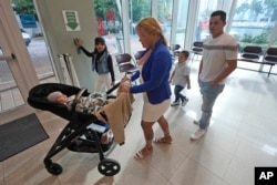 Aaron Rodriguez, right, and Cindy Baneza, center, leave an immigration court in Miami, Wednesday, Jan. 10, 2024, after a judge granted them more time to find an attorney to file for asylum. (AP Photo/Wilfredo Lee)