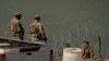 FILE - Guardsmen talk with migrants trying to cross the Rio Grande from Mexico into the U.S. near in Eagle Pass, Texas, July 11, 2023.
