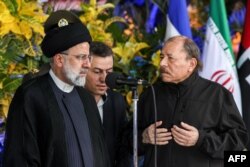This handout picture provided by the Iranian presidency shows Nicaragua's President Daniel Ortega, right, welcoming Iran's President Ebrahim Raisi at the Olof Palme Convention Centre in Managua on June 13, 2023. (Photo by Iranian Presidency/AFP)