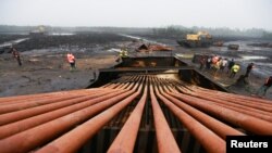 FILE - Members of the task force on illegal crude oil bunkering and artisanal refinery stand close to a distillation tank during the destruction of Bakana ii illegal artisanal camp in Okrika, Rivers state, Nigeria, Jan. 28, 2022. 
