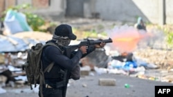 FILE - A policeman shoots tear gas at protesters during a demonstration calling for the resignation of Prime Minister Ariel Henry in Port-au-Prince on Feb. 7, 2024. Special police units were deployed across the city on Feb. 29, 2024, as violence swept through the area.