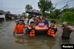 Petugas Badan Penanggulangan Bencana Daerah (BPBD) menggunakan perahu karet untuk mengevakuasi warga di kawasan pemukiman yang terkena dampak banjir akibat hujan lebat, di Padang, provinsi Sumatera Barat, 8 Maret 2024. (Antara Foto/Iggoy el Fitra/ via REUTERS)