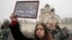 A woman holds a portrait of Alexey Navalny and his wife, Yulia, captioned "Eternal love has no death," outside the Church of the Icon of the Mother of God Soothe My Sorrows, where his funeral took place, in Moscow, Russia, March 1, 2024.