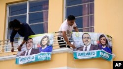 Seed Movement backers place banners with photos of their presidential candidate Bernardo Arevalo and running mate Karin Herrera at his office in Guatemala City, July 13, 2023. A court granted an injunction Thursday to block the suspension of the party.