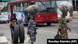 Seorang pria menggelindingkan ban mobil di sebuah jalan di Lagos, Nigeria, 5 September 2012. (Foto: Sunday Alamba/AP Photo/Ilustrasi)