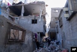 Palestinians inspect a damaged building following Israeli airstrikes on the town of Khan Younis, Gaza, Dec. 3, 2023.