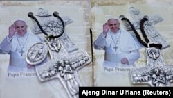 Foto Paus Fransiskus dipajang di samping salib di toko Avila menjelang kunjungannya, Jakarta, 31 Agustus 2024. (Foto: REUTERS/Ajeng Dinar Ulfiana)