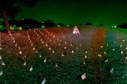 An activist sits among flags placed near the Washington Monument to memorialize the 180,000 people who have died in from the Covid-19 pandemic in the U.S. Aug. 27, 2020, in Washington.