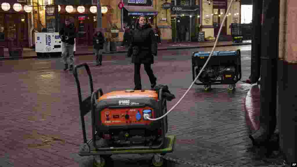 People walk on a street with many businesses powered by generators during a blackout in Kyiv, Ukraine.