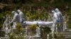 Workers wearing personal protective equipment (PPE) carry the body of a victim of the coronavirus disease at a Muslim cemetery in Gombak, outskirts of Kuala Lumpur, Malaysia, Feb. 5, 2021.