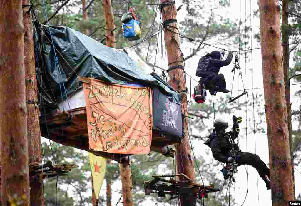 A German police officer and an activist are pictured in a protest camp where activists set up tree houses in a forest to protest against the expansion of the Tesla Gigafactory in Gruenheide near Berlin.