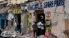 FILE - People stand at the entrance of a destroyed building after a deadly siege by al-Shabab militants in Mogadishu, Somalia, Aug. 21, 2022.