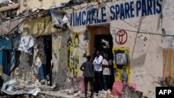 FILE - People stand at the entrance of a destroyed building after a deadly siege by al-Shabab militants in Mogadishu, Somalia, Aug. 21, 2022.