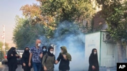 Polisi menembakkan gas air mata untuk membubarkan pendemo yang mengelar aksi di depan Universitas Teheran, Iran, pada 1 Oktober 2022. Para pendemo memprotes kematian Mahsa Amini yang tewas dalam tahanan polisi moral Iran. (Foto: AP)