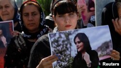 A woman holds a placard during a protest following the death of Mahsa Amini in front of the United Nations headquarters in Erbil, Iraq Sept. 24, 2022.