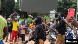 Soldiers carrying heavy weapons escort the convoy of Burkina Faso's self-declared new leader Ibrahim Traore as he arrives at the national television standing in an armoured vehicle in Ouagadougou, Burkina Faso, Oct. 2, 2022.
