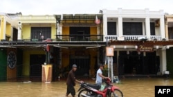 People push a motorbike in a flooded street following the passage of typhoon Noru in Hoi An city, Quang Nam province on Sept. 28, 2022.