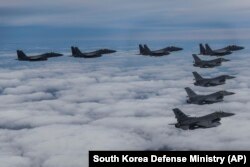 In this photo provided by South Korea Defense Ministry, South Korean Air Force's F15K fighter jets and U.S. Air Force's F-16 fighter jets, fly in formation during a joint drill in an undisclosed location in South Korea, Tuesday, Oct. 4, 2022. The South Ko