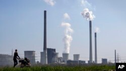 FILE - A mother pushes a stroller in front of the Scholven coal-fired power station, in Gelsenkirchen, Germany, March 28, 2022.