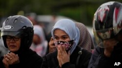 People pray for the victims of Saturday's soccer match stampede outside the Kanjuruhan Stadium in Malang, Indonesia, Monday, Oct. 3, 2022.