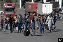 A group of Russians walk after crossing the border at Verkhny Lars between Georgia and Russia in Georgia, Sept. 27, 2022. After President Vladimir Putin ordered a partial mobilization to bolster his troops in Ukraine, many Russians are leaving their homes.