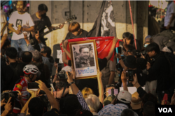 A protester holds up a picture of Thai Prime Minister Prayut Chan-o-Cha during protests beside Victory Monument in Bangkok, Thailand, Oct. 1, 2022, (Tommy Walker/VOA)
