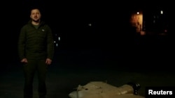 In a screen grab from video released by Ukraine's Presidential Press Service Oct. 27, 2022, President Volodymyr Zelenskyy is seen speaking next to what appears to be the wreckage of a downed drone.