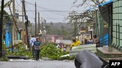 Orang-orang membersihkan jalan di Consolacion del Sur, Kuba, setelah dihantam badai Ian, 27 September 2022. (ADALBERTO ROQUE / AFP)