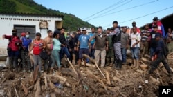 Lawmaker Diosdado Cabello, center right with face mask, tells Venezuela's President Nicolas Maduro where to walk during a visit the area flooded in Las Tejerias, Venezuela, Oct. 10, 2022. A fatal landslide fueled by flooding and rain swept through this town in central Venezuela.