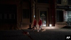 People walk with their dogs on a street in Zaporizhzhia, Ukraine, Oct. 19, 2022. 