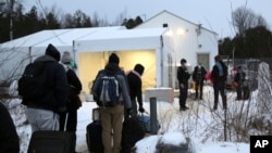 Sejumlah migran mengantre di pusat penerimaan individu yang menyebrangi perbatasan secara tidak resmi di Saint-Bernard-de-Lacolle, Quebec, Kanada, pada 12 Januari 2022. Para migran itu menyeberang dari AS. (Foto: AP/wilson Ring)