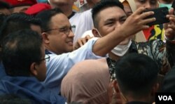 Anies Baswedan (tengah) melakukan swafoto dengan pendukungnya setelah dirinya resmi menyelesaikan tugasnya selama 5 tahun dari 2017 hingga 2022 sebagai gubernur DKI Jakarta pada 16 Oktober tahun ini. (VOA/Indra Yoga)