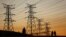 FILE - Locals walk past electricity pylons in Soweto, South Africa, July 3, 2022. Matshela Koko, the former head of the country's power provider Eskom has been charged with multiple counts related to corruption, fraud and money laundering.
