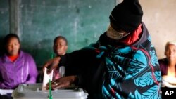 A woman covered with a blanket casts her vote at a poling station in Maseru, Lesotho, Oct. 7, 2022. 