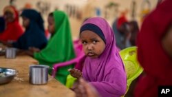 FILE - A child eats at a school in Dollow, Somalia, Sept. 19, 2022. At midday, dozens of hungry children from the camps try to slip into a local primary school where the World Food Program offers a lunch program for students.