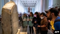 FILE - Visitors view the Rosetta Stone at the British Museum in London on July 26, 2022.