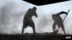 Sejumlah pekerja tampak memindahkan batu bara ke dalam sebuah truk di pinggiran Kota Kabul, Afghanistan, pada 20 Oktober 2022. (Foto: AFp/Wakil Kohsar)