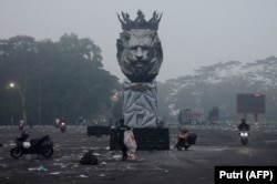 Pengendara motor mudik di luar Stadion Kanjuruhan pada pagi hari usai pertandingan sepak bola antara Arema FC dan Persebaya Surabaya di Malang, Jawa Timur, 2 Oktober 2022. (Foto: AFP/Putri)