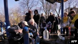 Kyiv residents fill plastic containers and bottles at a water pump in one of the parks in the Ukrainian capital Kyiv on Oct. 31, 2022.